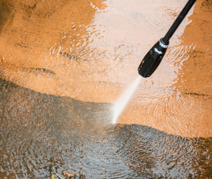 Hochdruckreiniger entfernt Schmutz von einer Steinplatte, sichtbar durch den Unterschied zwischen gereinigtem und verschmutztem Bereich