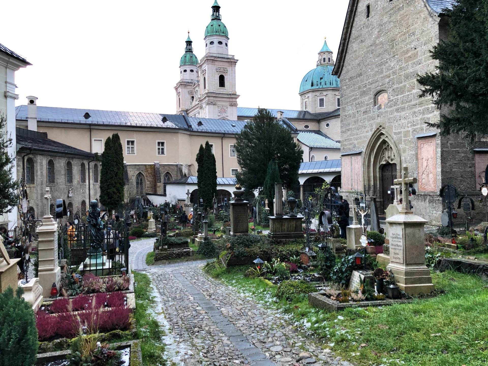 Friedhof mit Grabsteinen und Wegen vor historischen Kirchengebäuden mit grünen Kuppeln und Türmen